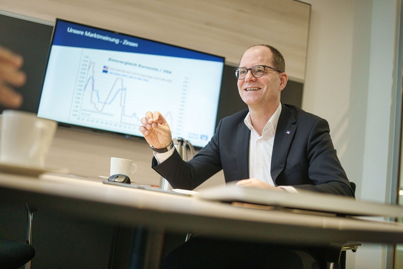 Kundenbetreuer sitzt Kunden im Büro gegenüber und lächelt ihn an