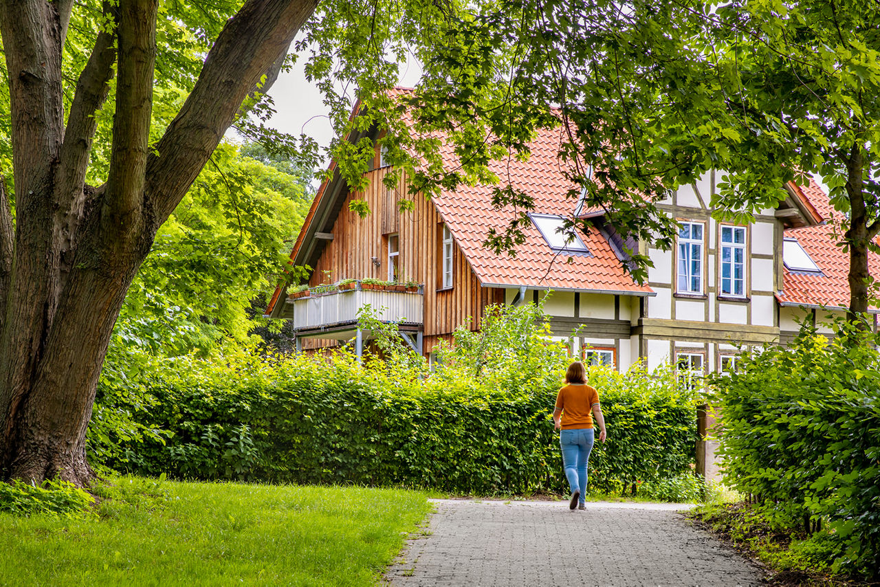 Bild Startseite voba4home, Frau öäfut auf einbem Weg im Grünen mit Haus im Hintergund