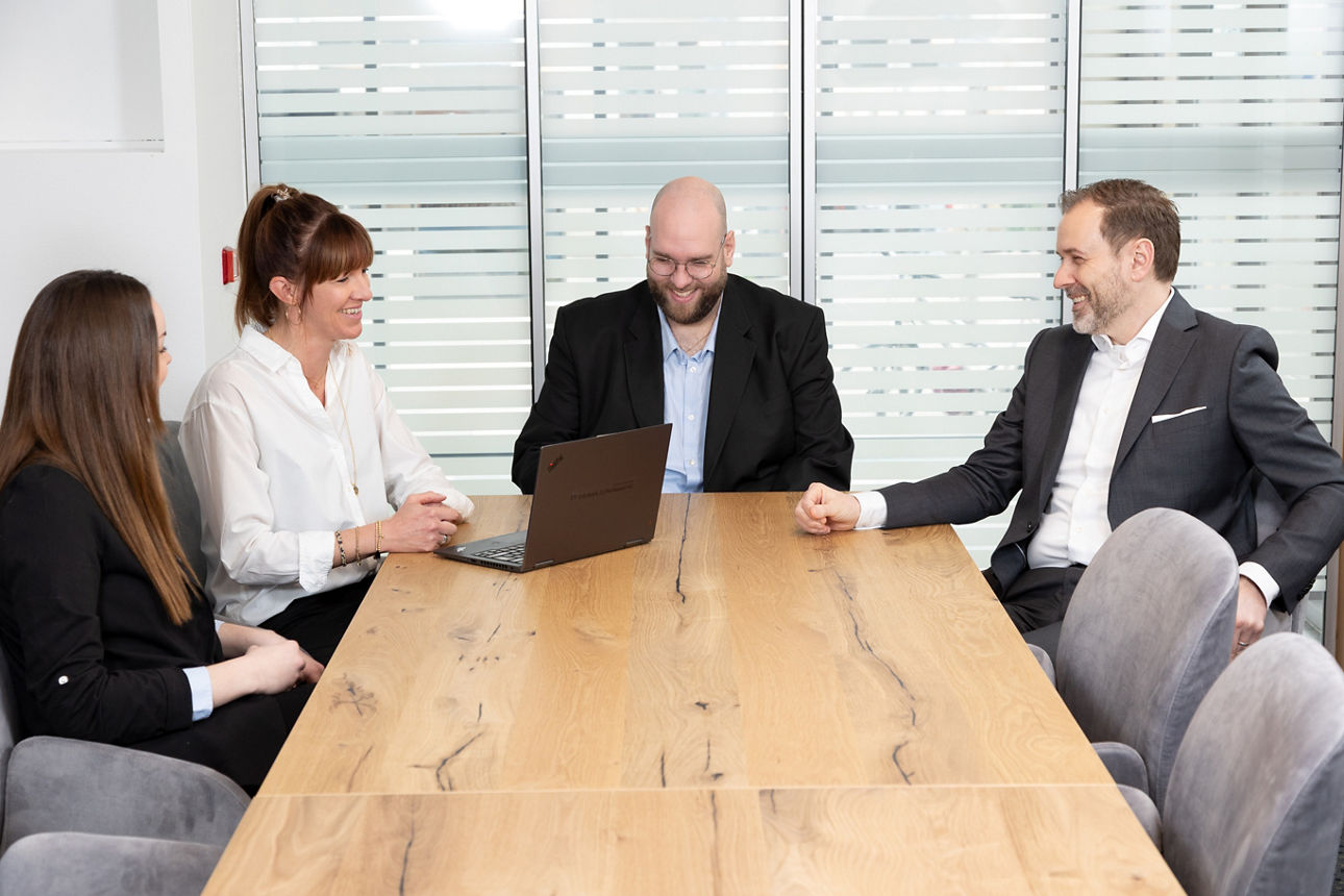 Vier Bankmitarbeiter sitzen an einem Besprechungstisch