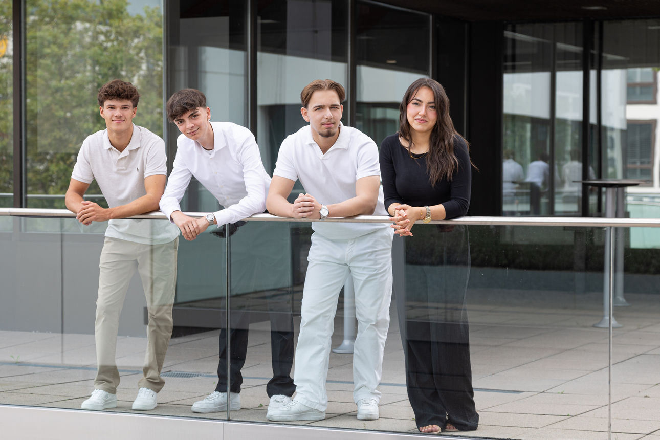 Vier Auszubildende vor einem Gebäude
