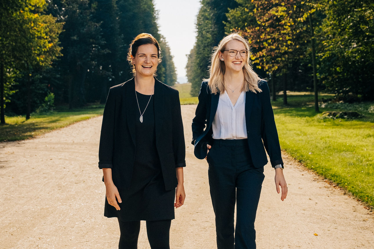 Zwei Frauen in Businesskleidung auf einer Treppe im Barockgarten