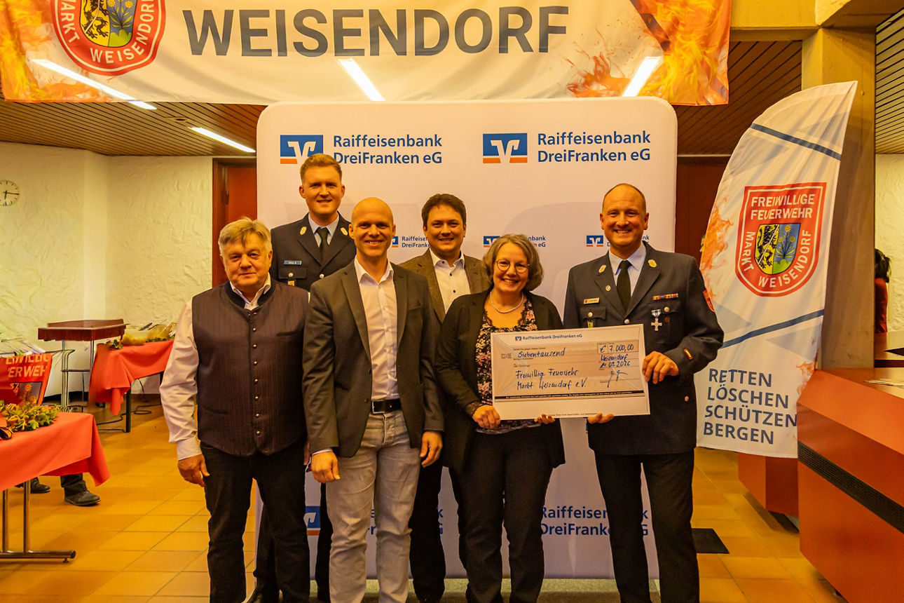 Vorstände der Feuerwehr, der Bank und Kundenberater präsentieren einen Scheck in Höhe von 7.000 Euro