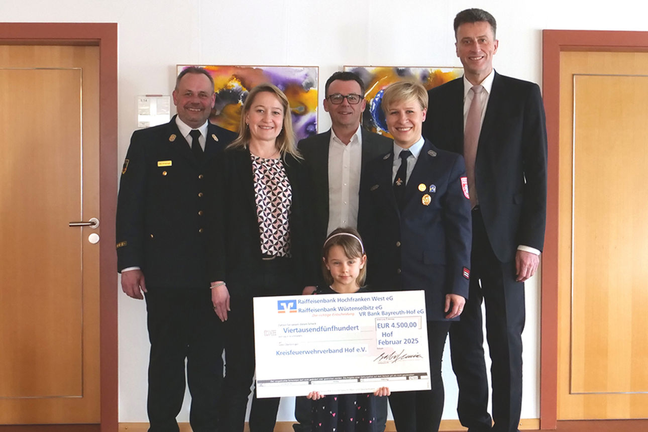 Männer, Frauen und ein Kind stehen mit einem Spendenscheck für ein Gruppenfoto bereit