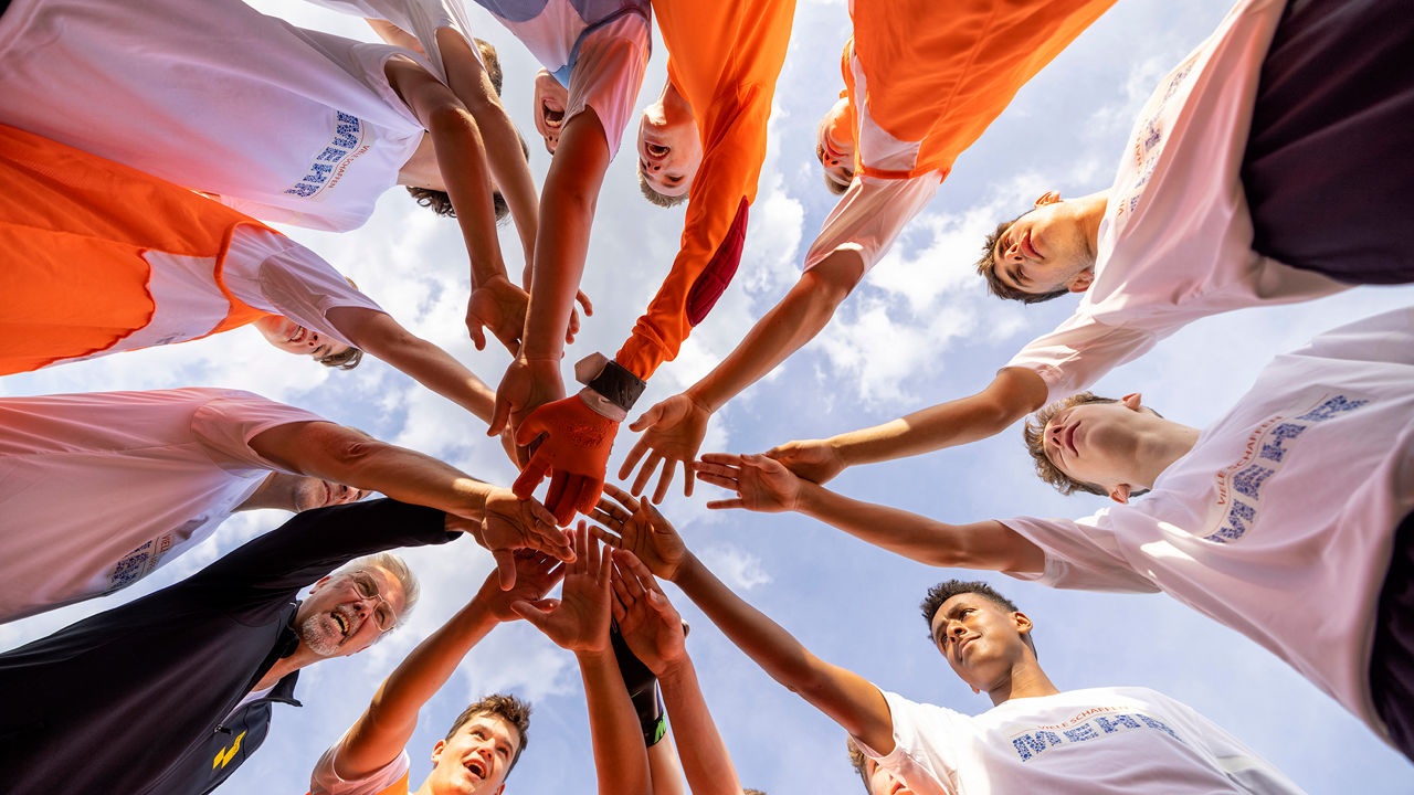 Ein Sportteam das zusammensteht und ihr Hände übereinanderlegt
