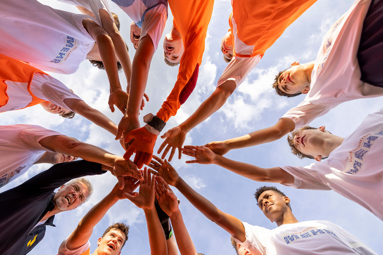 Ein Sportteam das zusammensteht und ihr Hände übereinanderlegt
