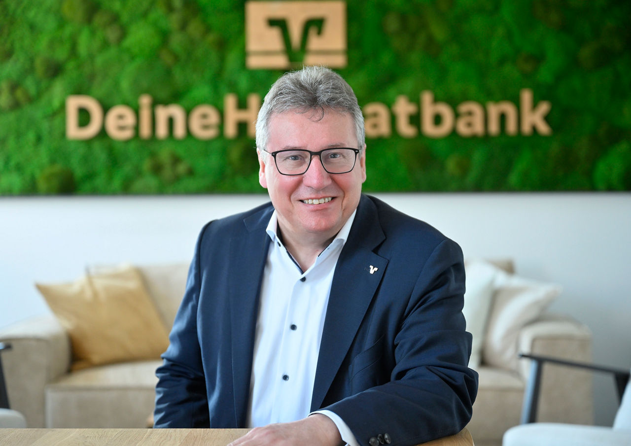 Vorstandsmitglied Janhsen vor dem Heimatbanklogo