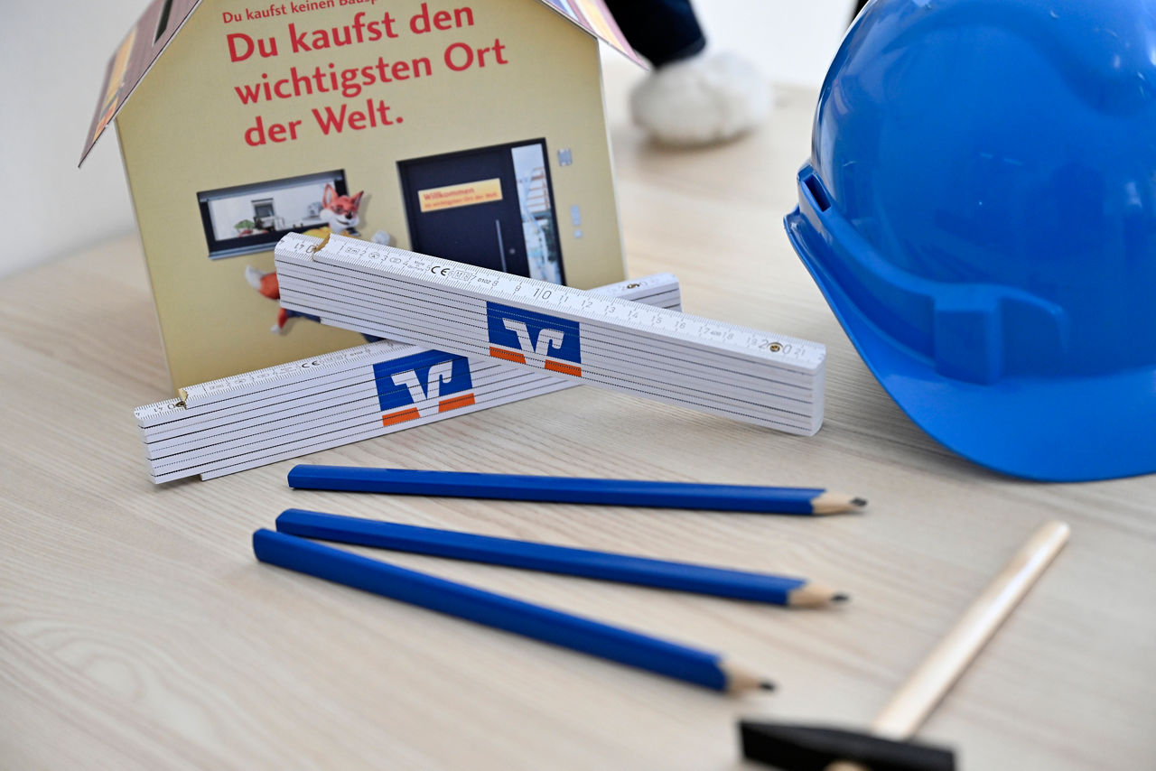 Bleistifte und Zollstöcke neben einem Bauhelm auf einem Tisch 