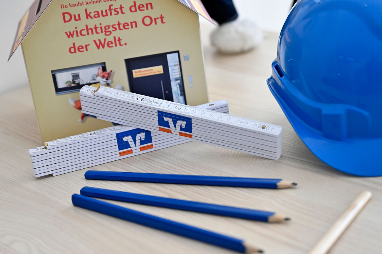 Bleistifte und Zollstöcke neben einem Bauhelm auf einem Tisch 