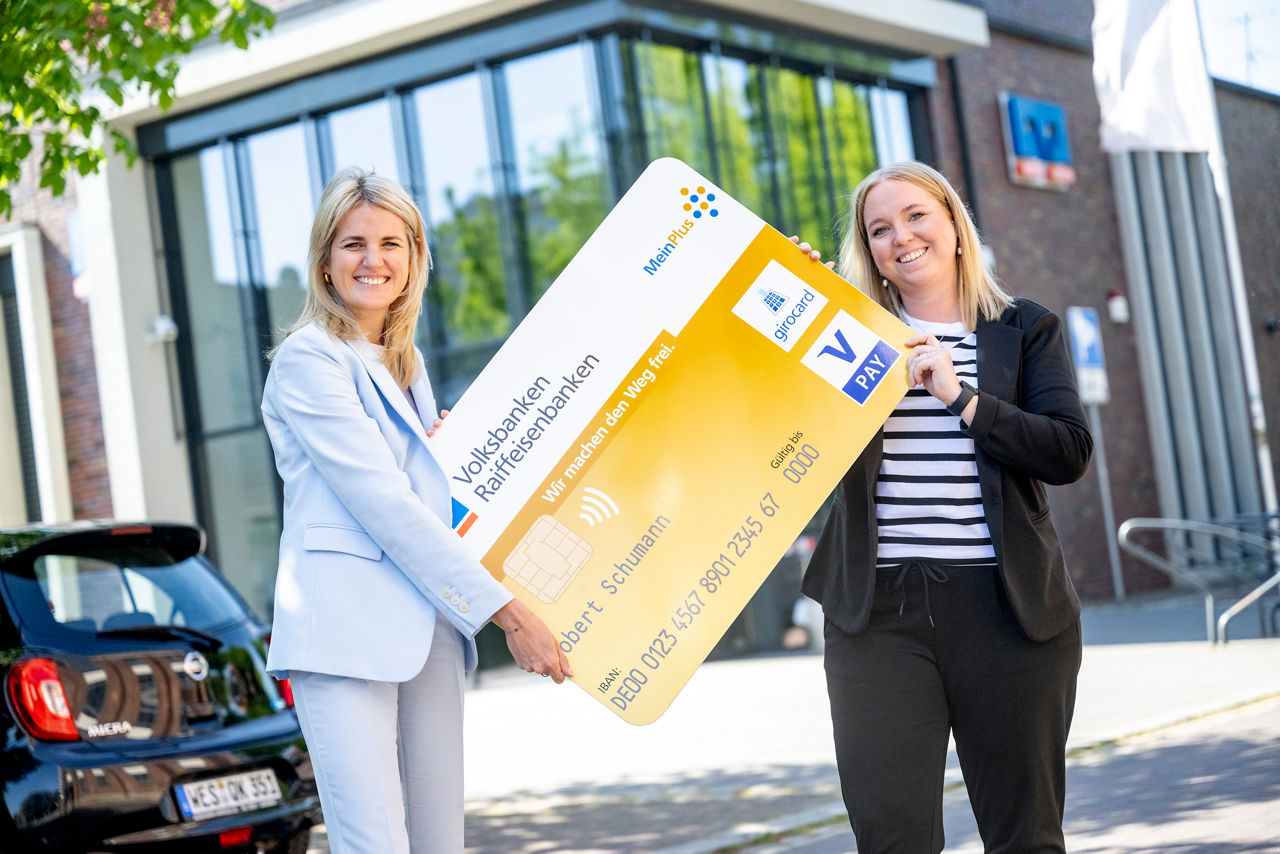 Zwei Mitarbeiterinnen vor der Bank mit der goldenen Kreditkarte