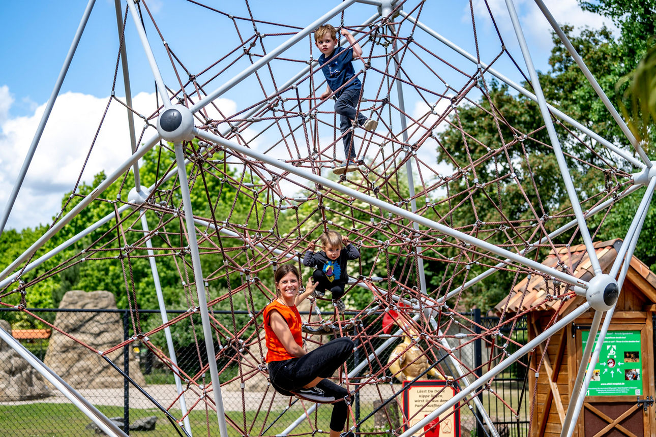 Eine Mutter ist mit ihren beiden Kindern im Klettergerüst