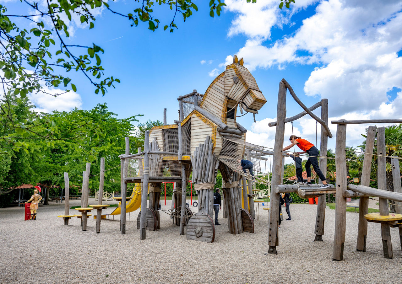 Ein Holzpferd als Klettergerüst und zwei Kinder mit ihrer Mama spielen darauf.