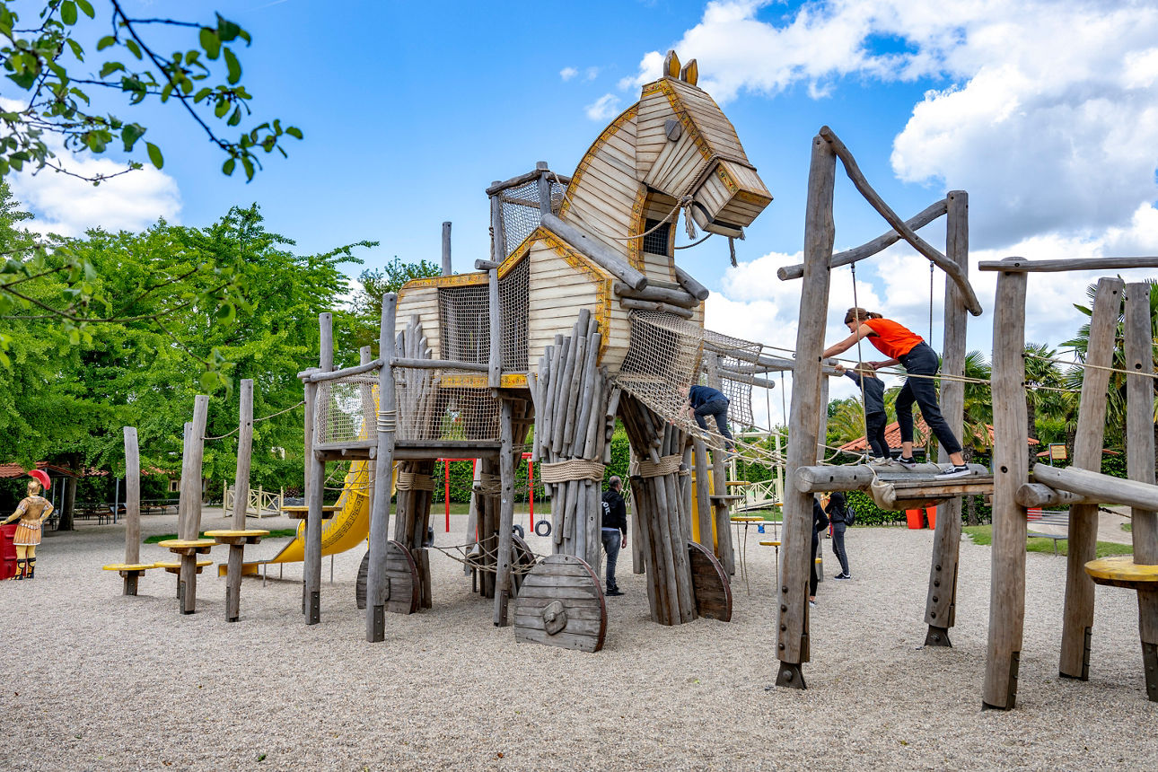 Ein Holzpferd als Klettergerüst und zwei Kinder mit ihrer Mama spielen darauf.
