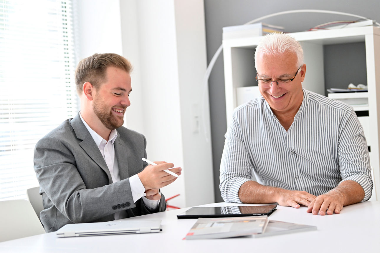 Berater und Kunde sitzen mit dem I Pad am Schreibtisch