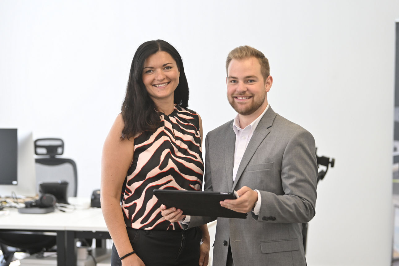 Kundin und Berater stehen im Büro mit einem Tablet in der Hand