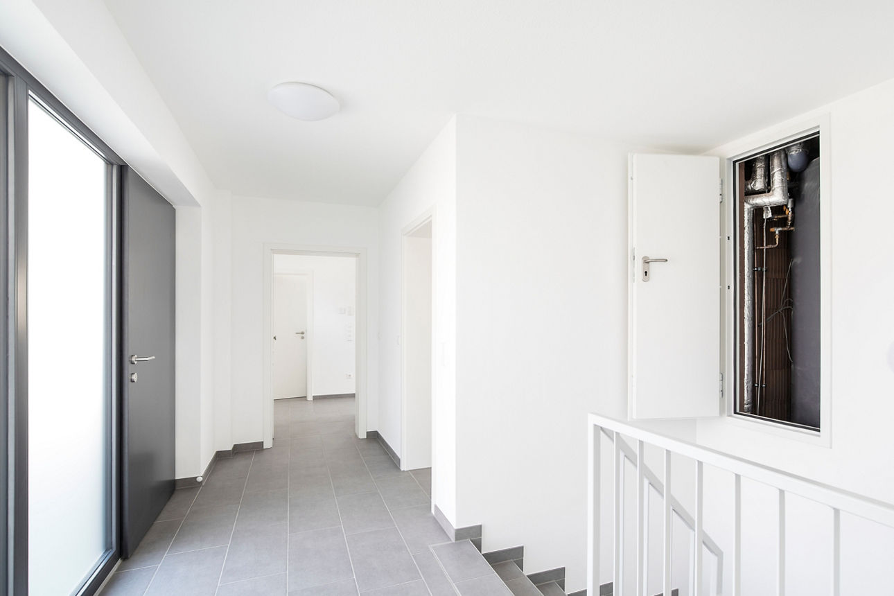 Der Eingangsbereich mit Treppe ins Untergeschoss eines modernen, energieautarken Hauses ist zu sehen.