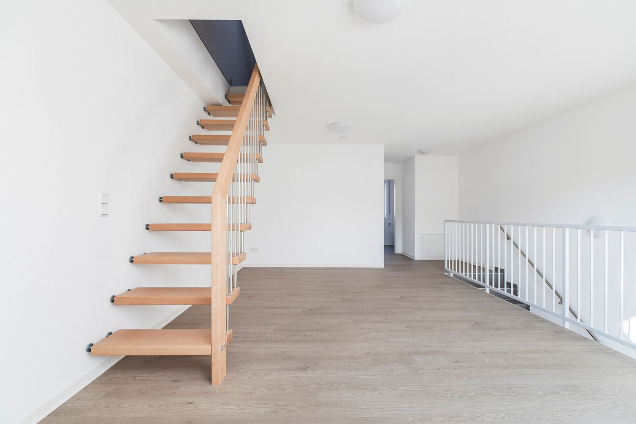 Darstellung des Arbeitszimmers im OG eines modernen, energieautarken Hauses. Zu sehen ist eine Holztreppe in den Dachspitz auf der linken Seite. Auf der rechten Seite ist die Treppe vom EG ins OG zu sehen. 