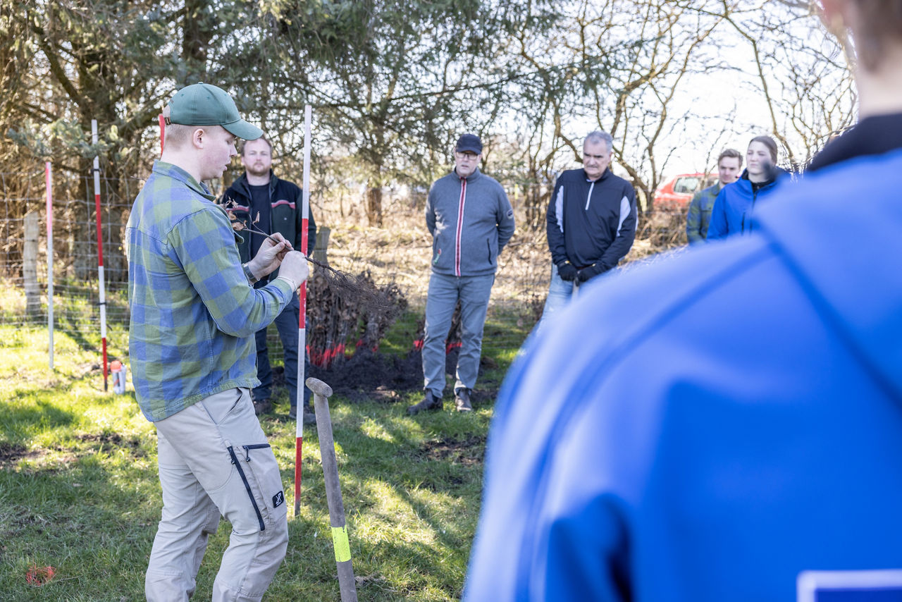 Eine Gruppe von Leuten steht mit einem Spaten auf einer Wiese