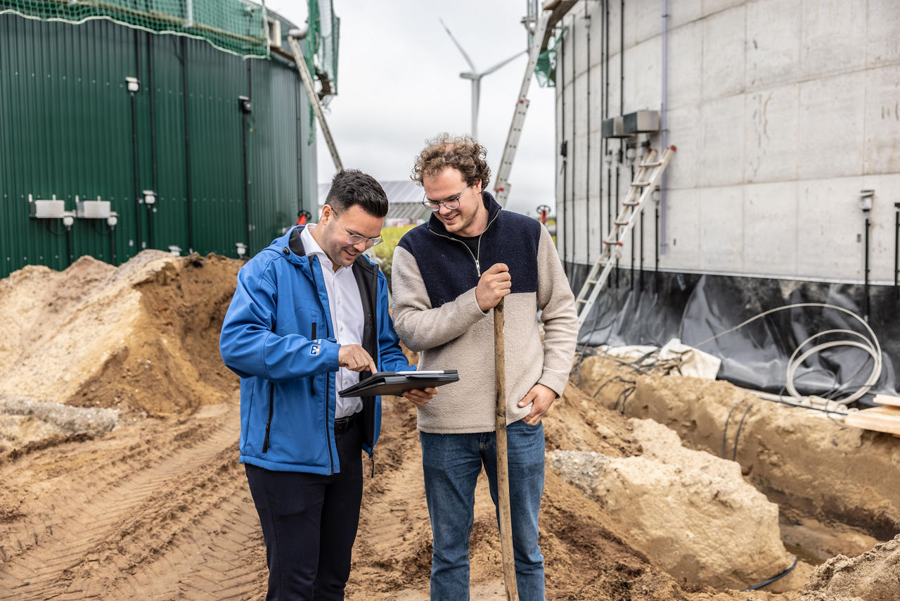 Agrarkundenbetreuer berät seinen Kunden vor eine Biogasanlage