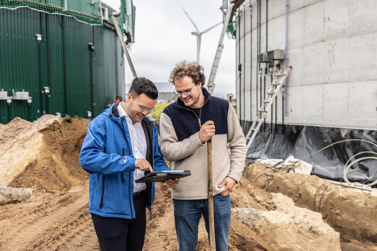 Agrarkundenbetreuer berät seinen Kunden vor eine Biogasanlage