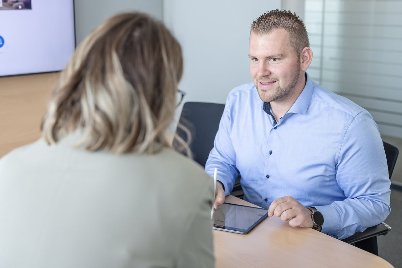 Firmenkundenbetreuer sitzt Kundin gegenüber und lächelt