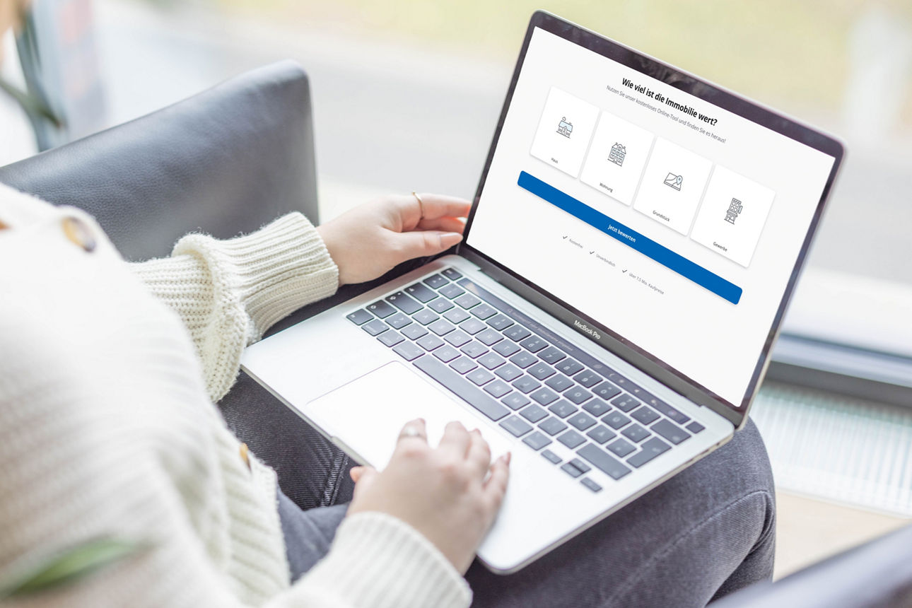 Eine junge Frau sitzt auf einem modernen Ledersessel und nutzt einen Laptop auf ihrem Schoß.