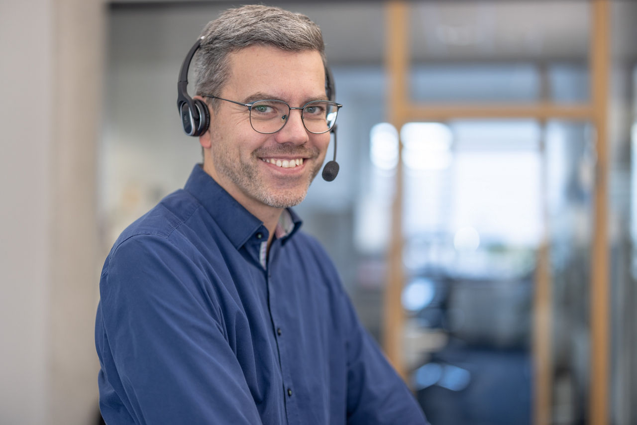 Freundlich lächelnder Mitarbeiter mit Headset auf