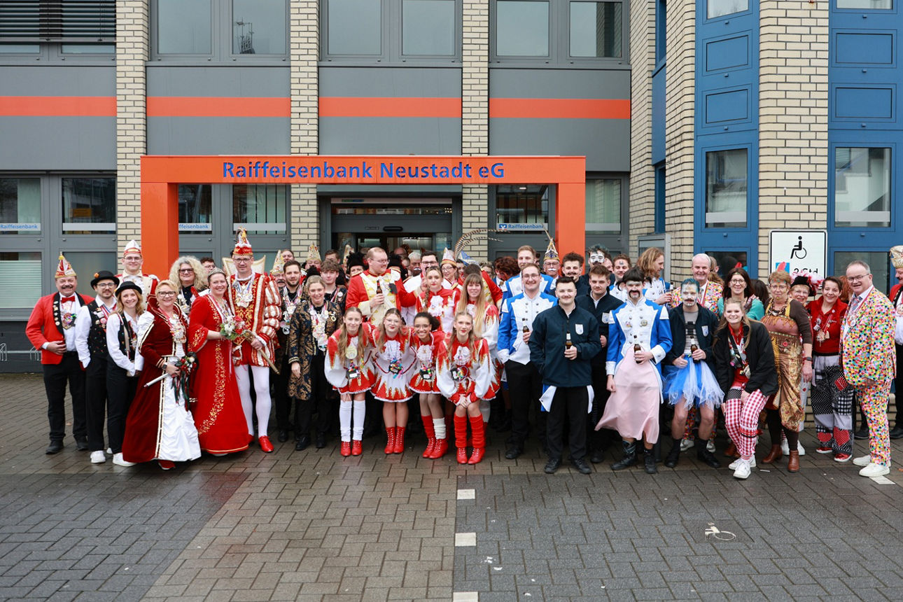 Gruppenfoto der Narrenschar und der Mitarbeitenden der Bank vor dem Eingang der Geschäftsstelle Asbach