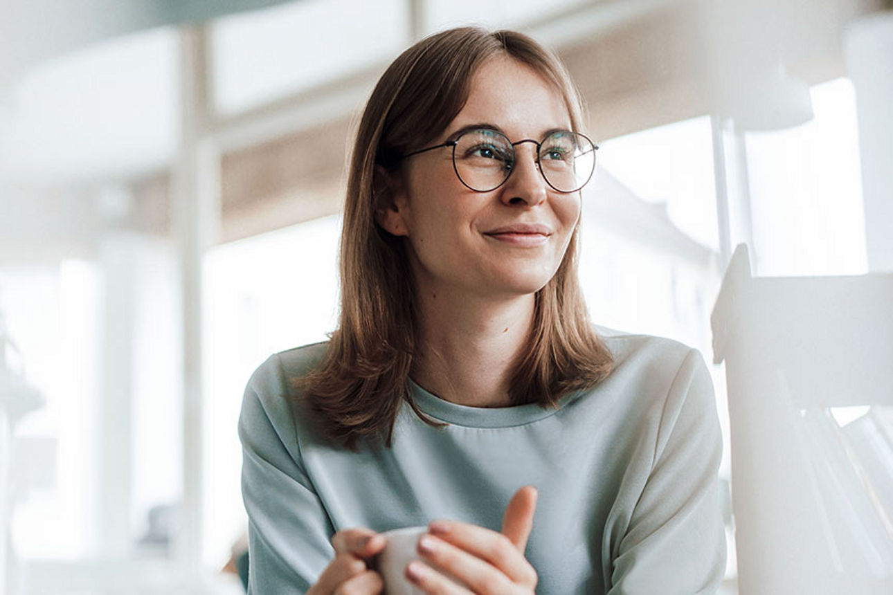 Lächelnde Frau, die eine Tasse in ihren Händen hält