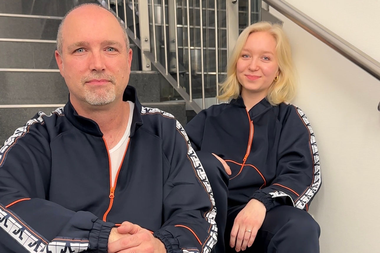 Zwei Personen sitzen lässig in einem Trainingsanzug auf einer Treppe.