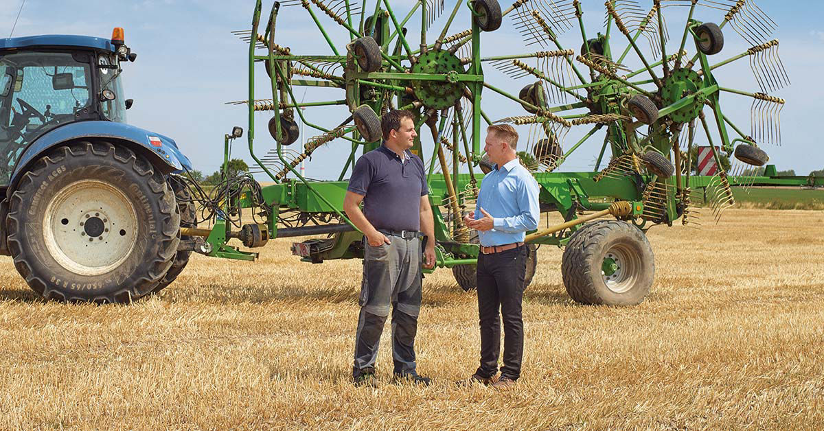 Zwei Landwirte stehen vor einem Traktor auf einem Feld