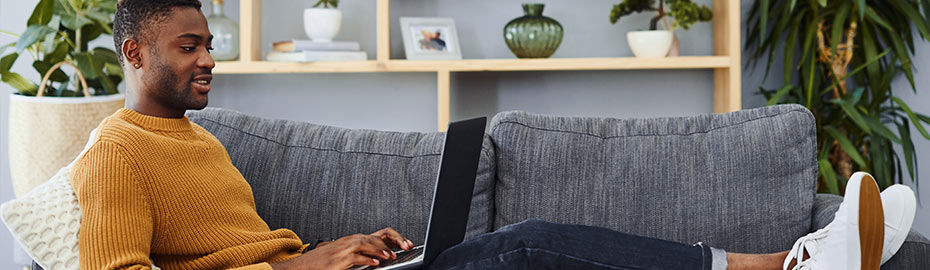 Mann am PC auf Sofa