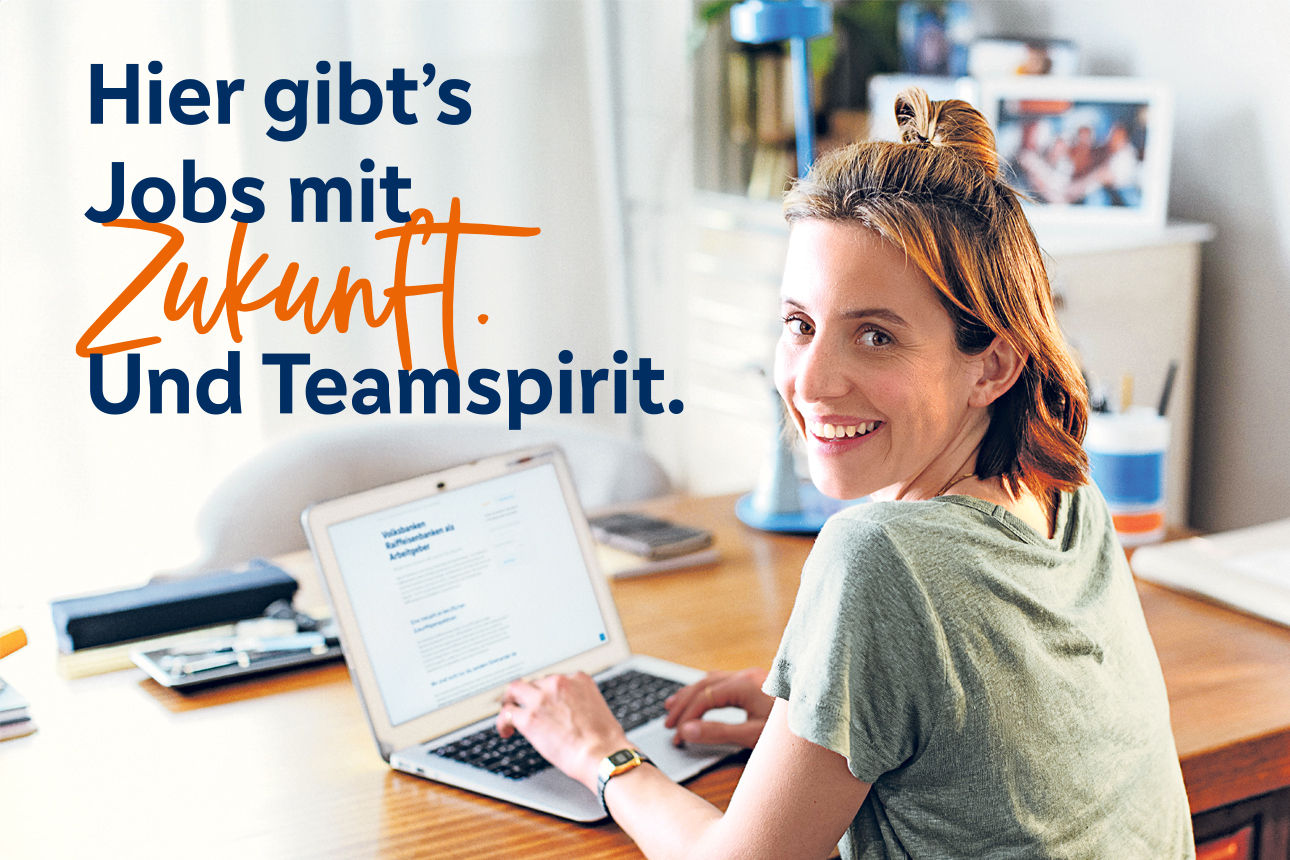 Eine junge Frau sitzt an einem Laptop und lächelt in die Kamera