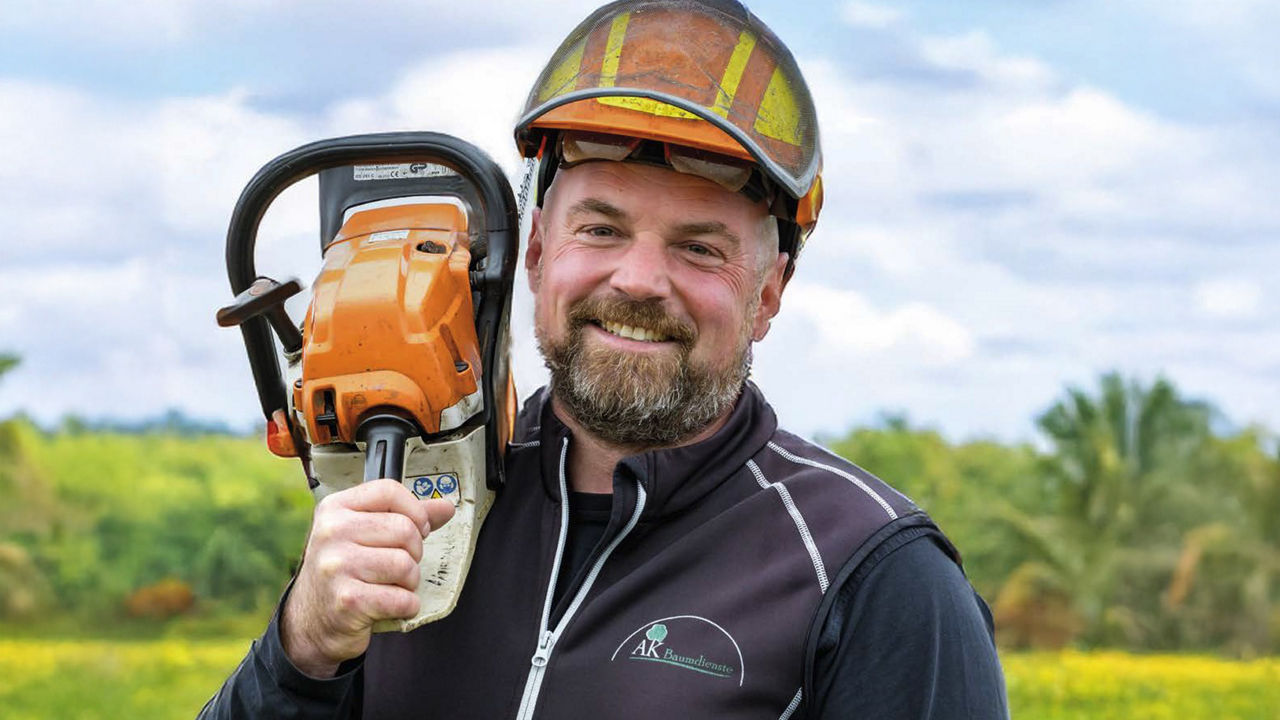 Alexander Kriwet mit Helm und Motorsäge auf der Schulter