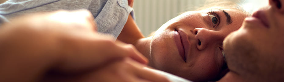 Ein Mann und eine Frau lächeln fröhlich, während sie zusammen im Bett liegen und eine warme und intime Atmosphäre schaffen.