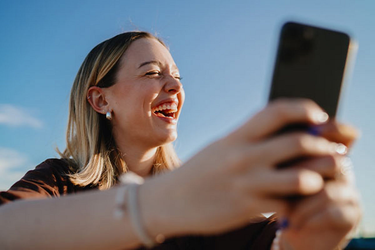 lachende junge Frau mit Smartphone