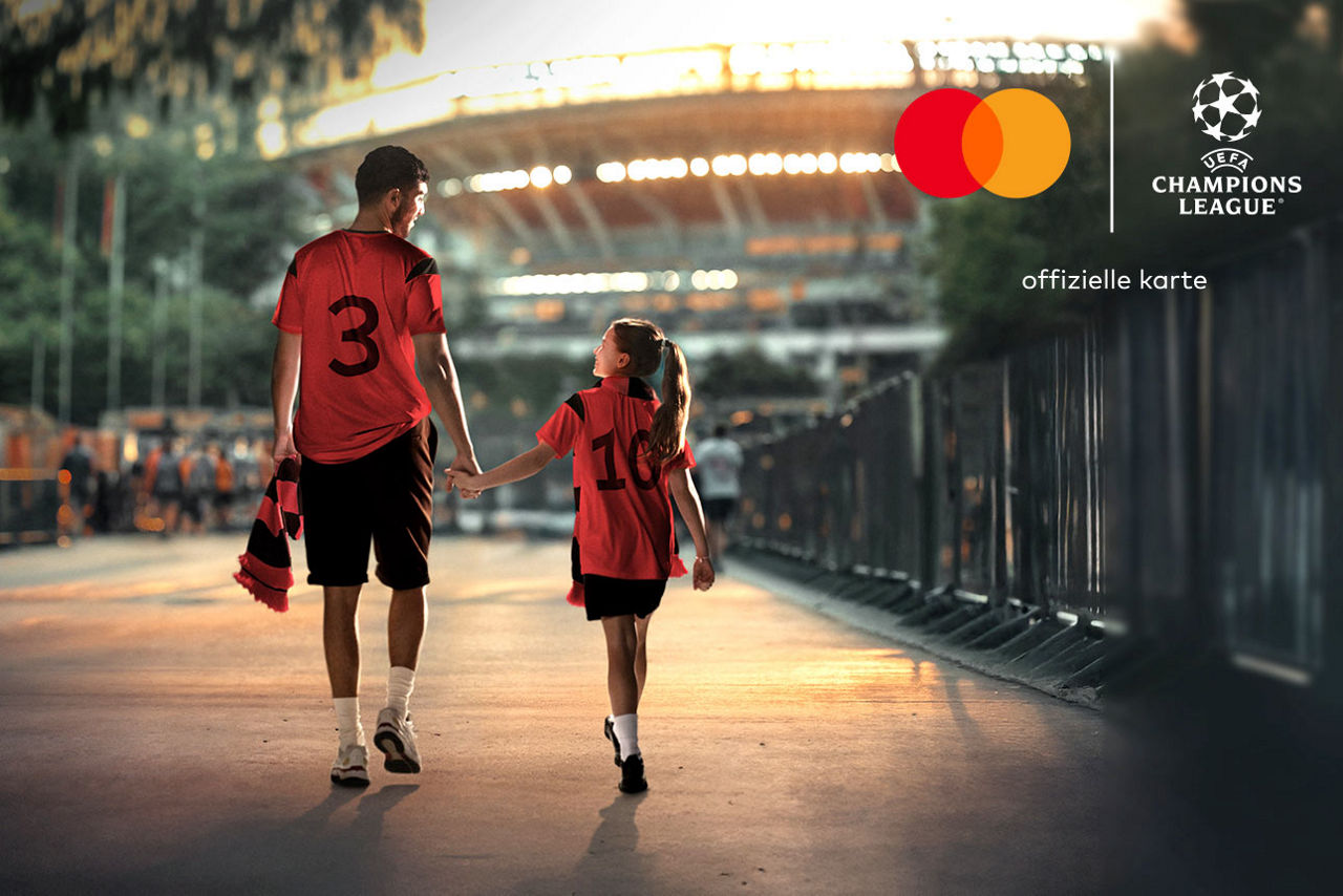 Ein Vater und sein Kind laufen Hand in Hand zum Stadion. Beide tragen Trikots und freuen sich auf das Spiel