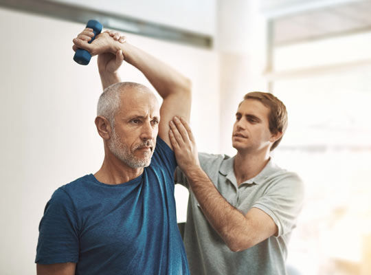 Ein Mann wird von einem Physiotherapeuten während der Reha-Maßnahme betreut