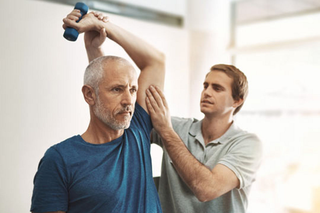 Ein Mann wird von einem Physiotherapeuten während der Reha-Maßnahme betreut