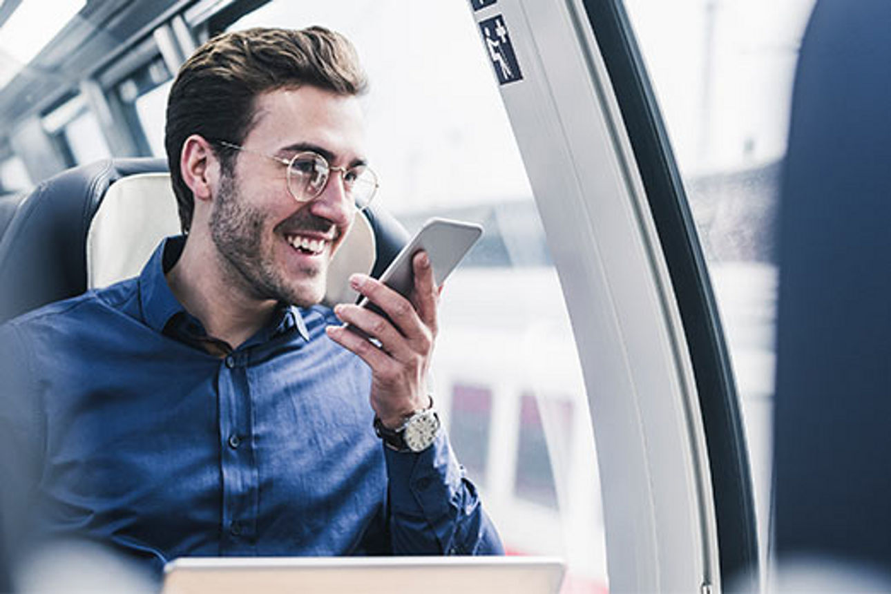 Mann sitzt im Zug und spricht in sein Smartphone