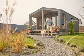 Ein Mann verlässt mit seinem weißen Hund das Haus über den Garten.  Ein Mann verlässt mit seinem weißen Hund das Haus über den Garten.