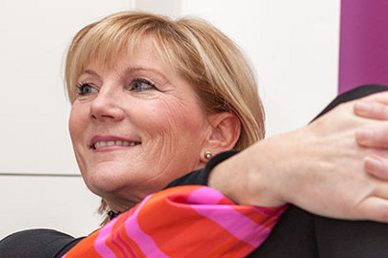 Eine Frau sitzt mit verschränkten Armen auf ihrem Schoß