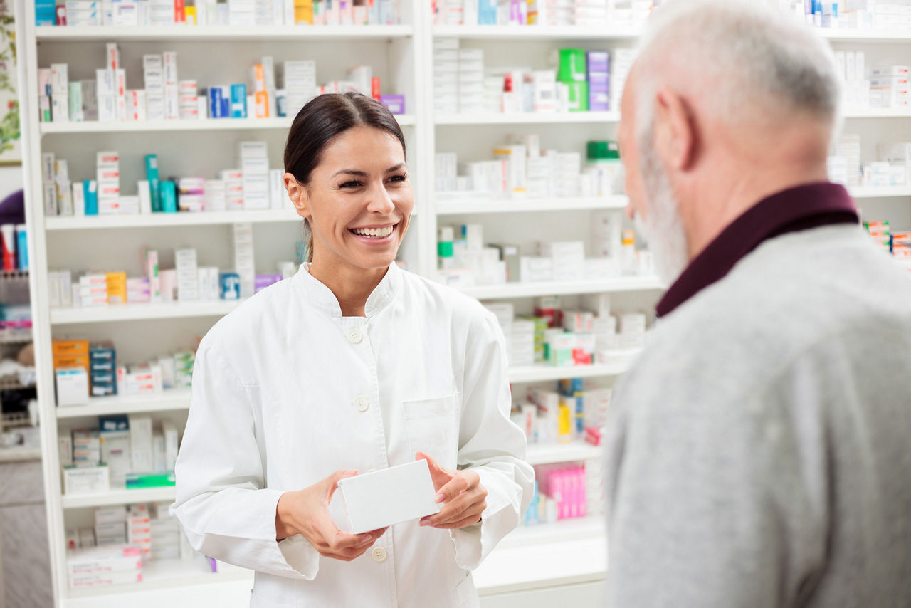 Freundliche Apothekerin, die Medikamente an einen älteren männlichen Kunden verkauft