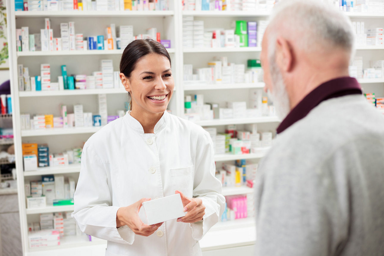 Freundliche Apothekerin, die Medikamente an einen älteren männlichen Kunden verkauft