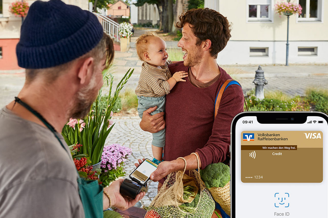 Junger Vater zahlt auf dem Markt entspannt mit Apple Pay