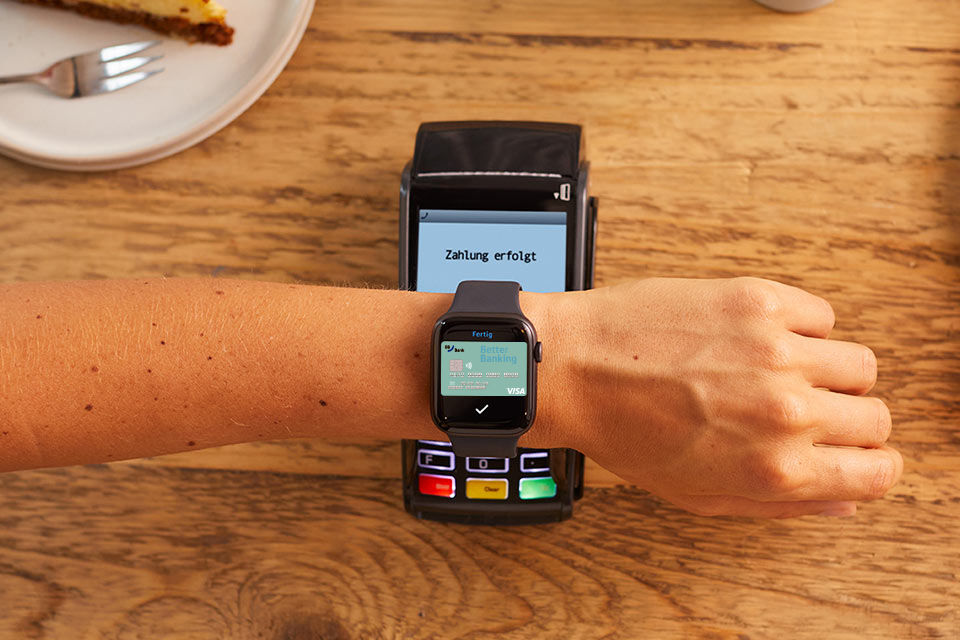 Bezahlen mit der Apple Watch- Arm mit Apple Watch und BBBank DirectCard über einem Bezahlterminal