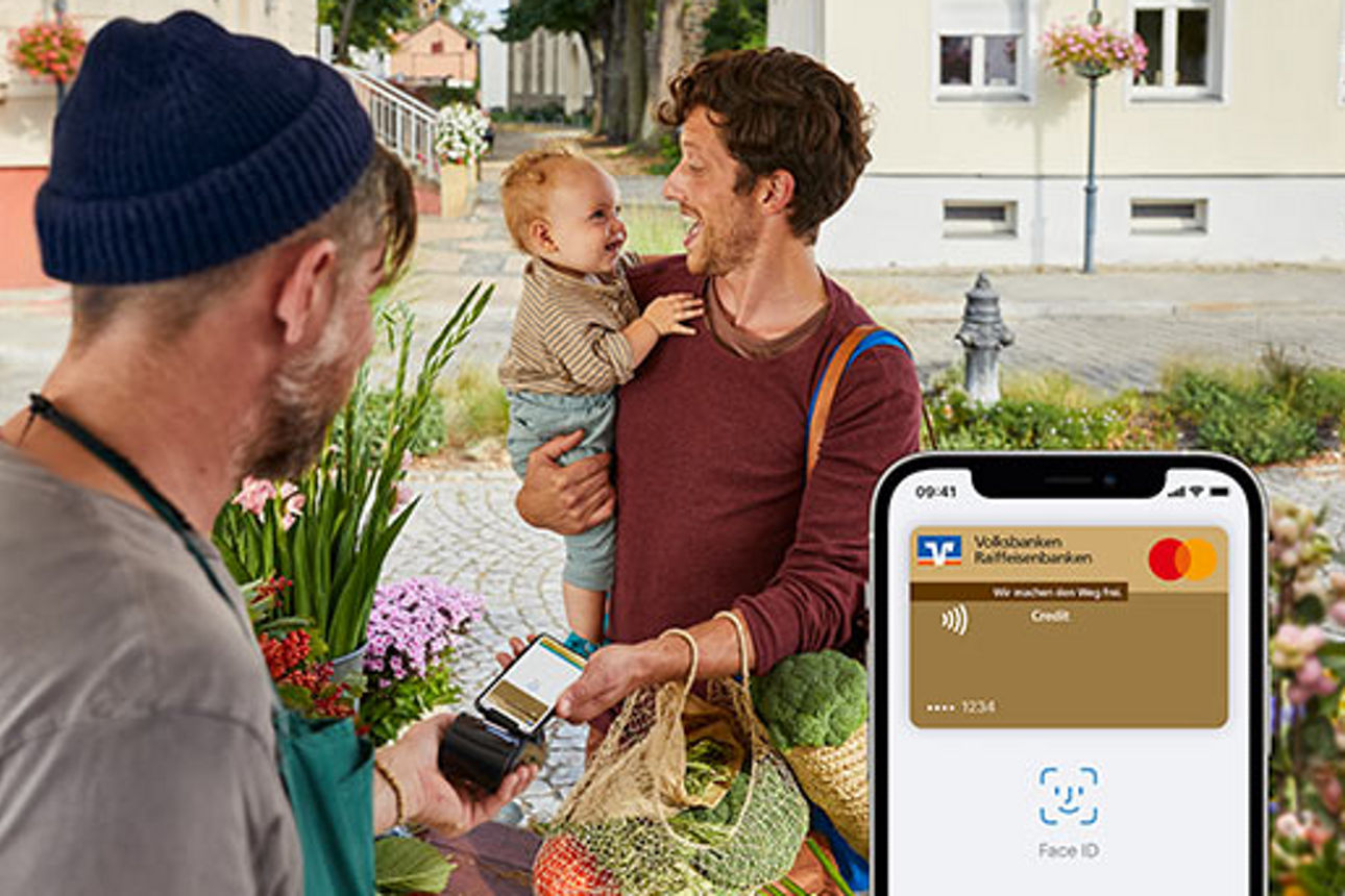 Mann mit Kind auf dem Arm bezahlt an Marktstand mit Apple Pay