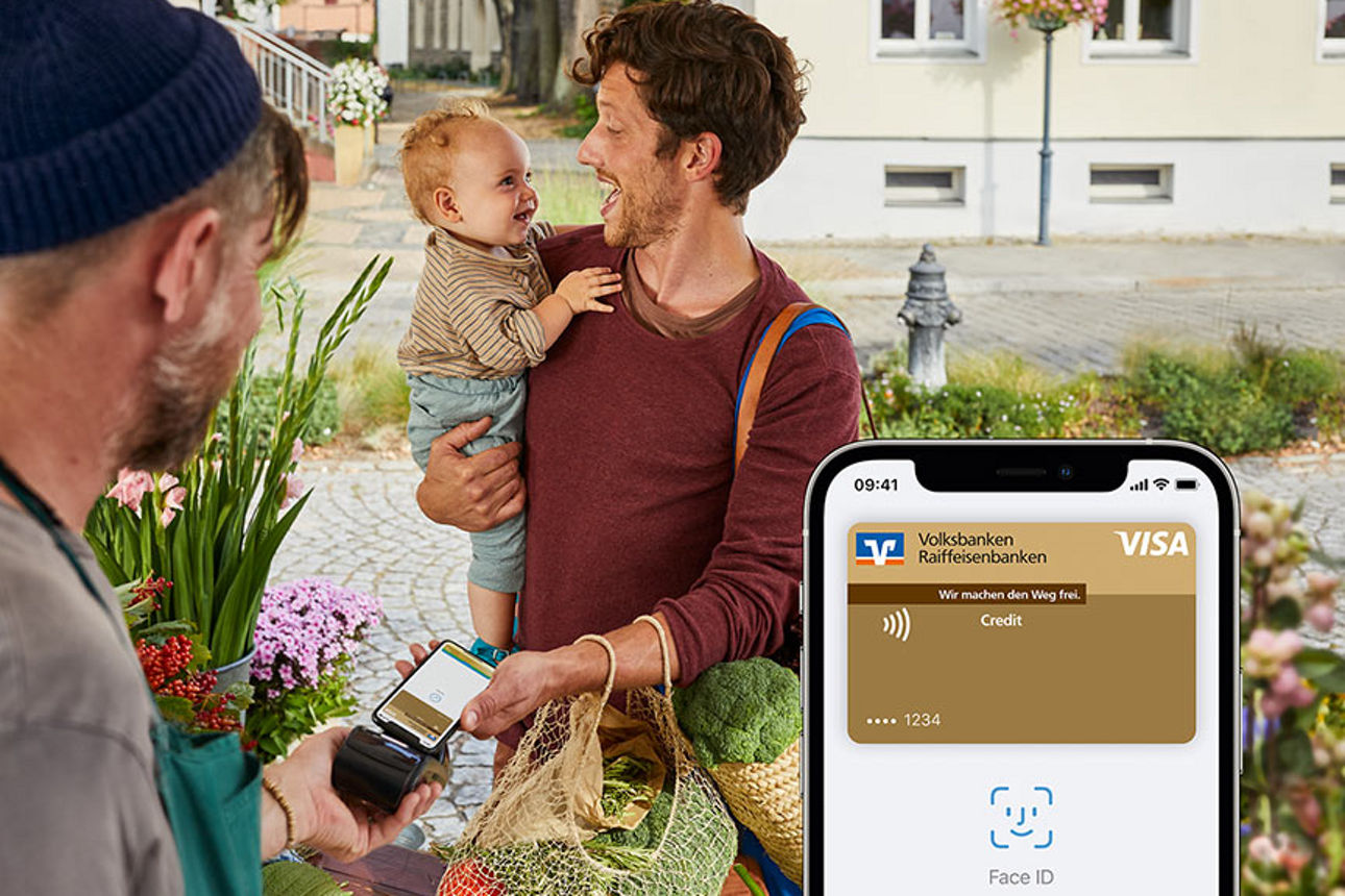 Mann mit Kind auf dem Arm bezahlt an Marktstand mit Apple Pay
