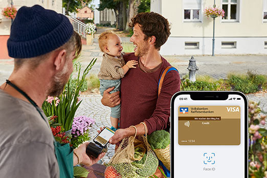 Mann mit Kind auf dem Arm bezahlt an Marktstand mit Apple Pay