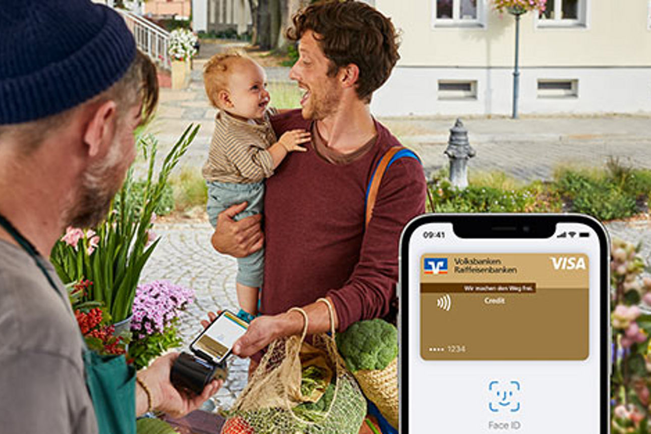 Mann mit Kind auf dem Arm bezahlt an Marktstand mit Apple Pay