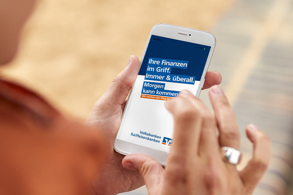 Frau hält Smartphone mit VR Banking App in der Hand